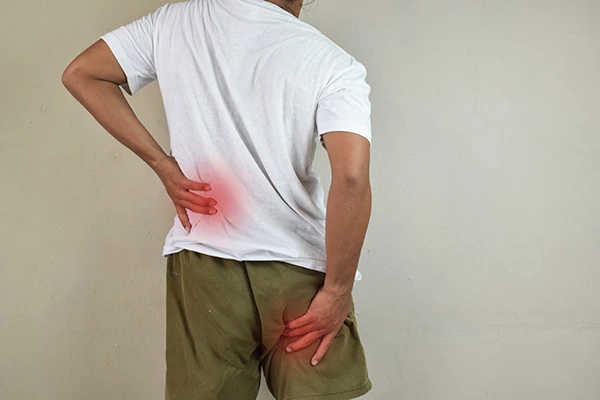 Homem de costas segurando a região lombar e o glúteo, indicando pontos de dor ciática.